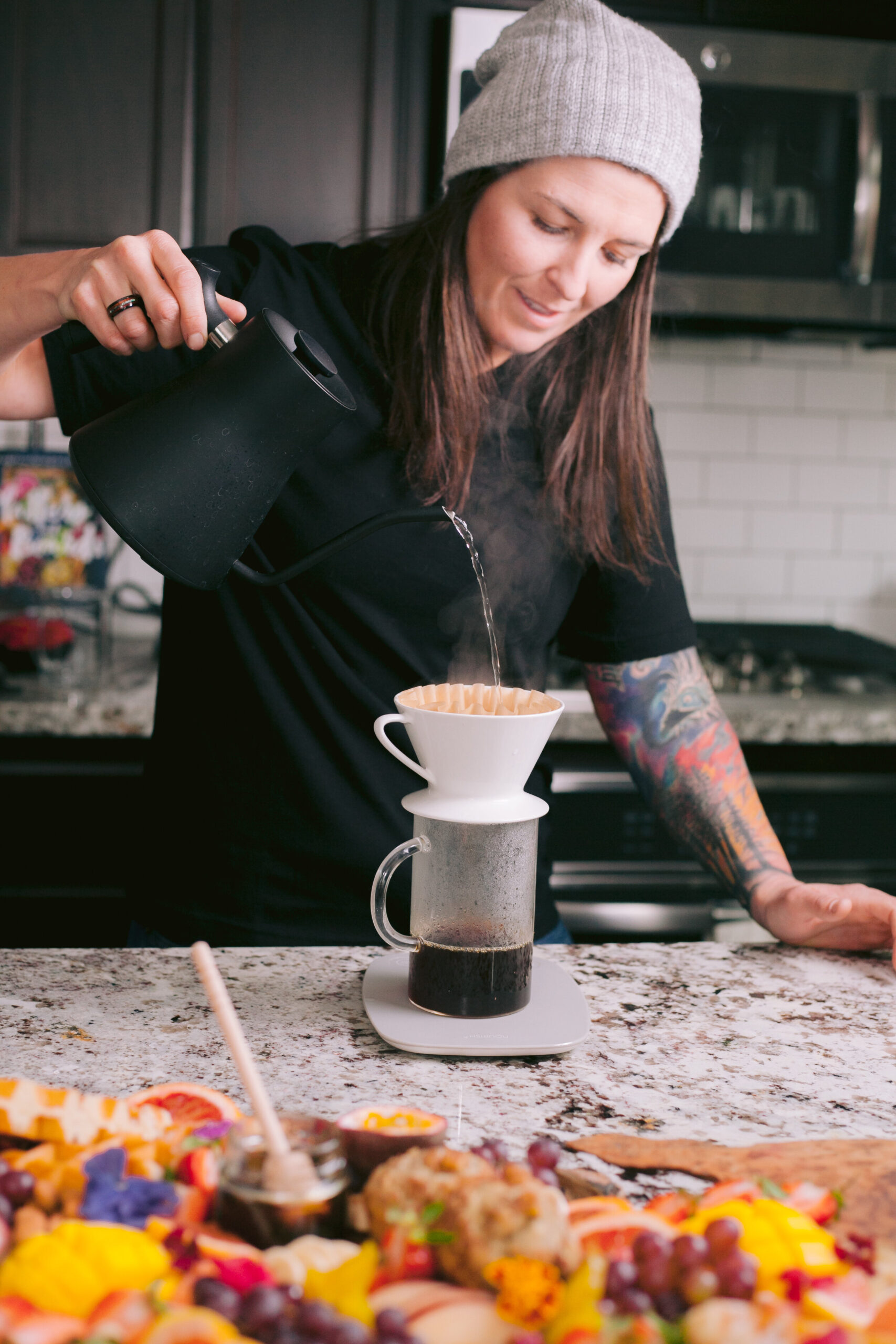  Woman pouring hot water over pour over brewer in kitchen. 