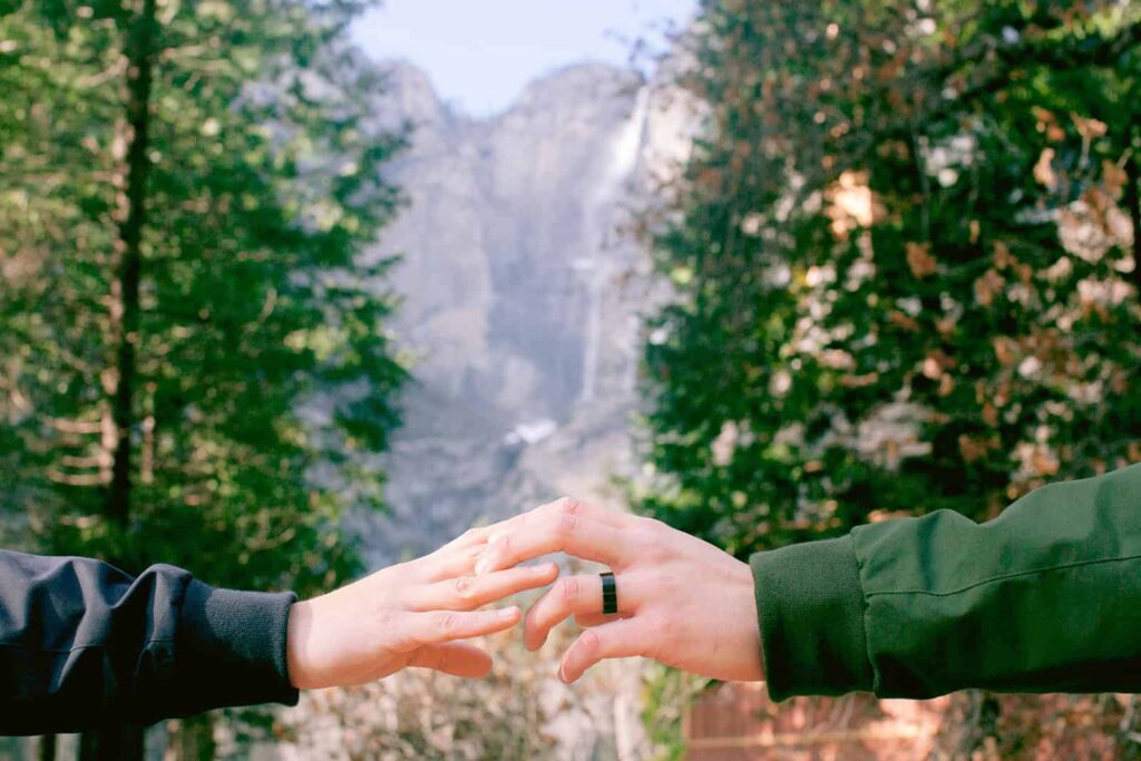 Two hands out stretched embracing after yosemite proposal with yosemite falls in the background