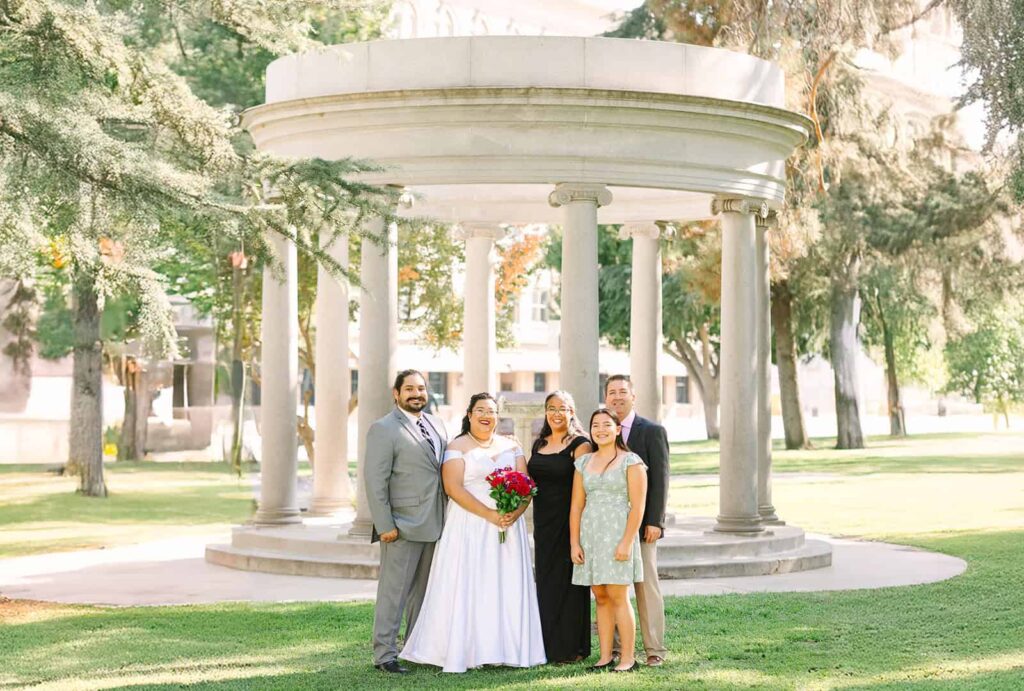 Bride and groom posing with family in front of Fresno Courthouse rotunda after their courthouse wedding