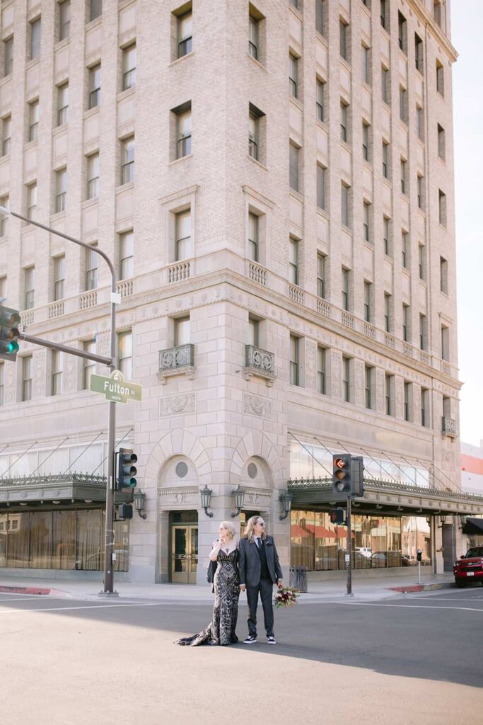 Bride and groom crossing a downtown Fresno street, holding hands and bouquet