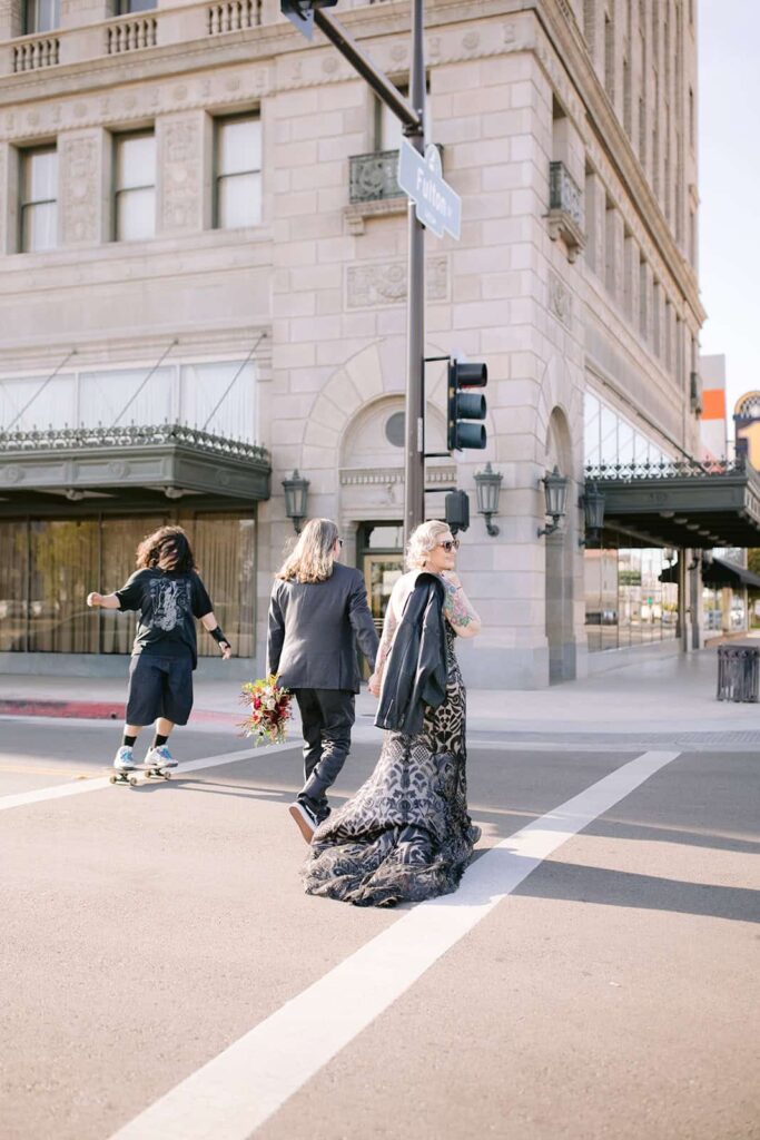 Bride and groom crossing a downtown Fresno street, holding hands and bouquet
