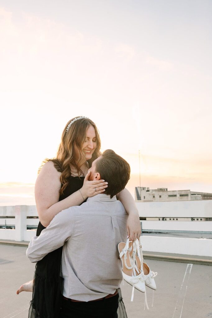 Groom lifting bride on rooftop with Fresno skyline in the background after courthouse wedding